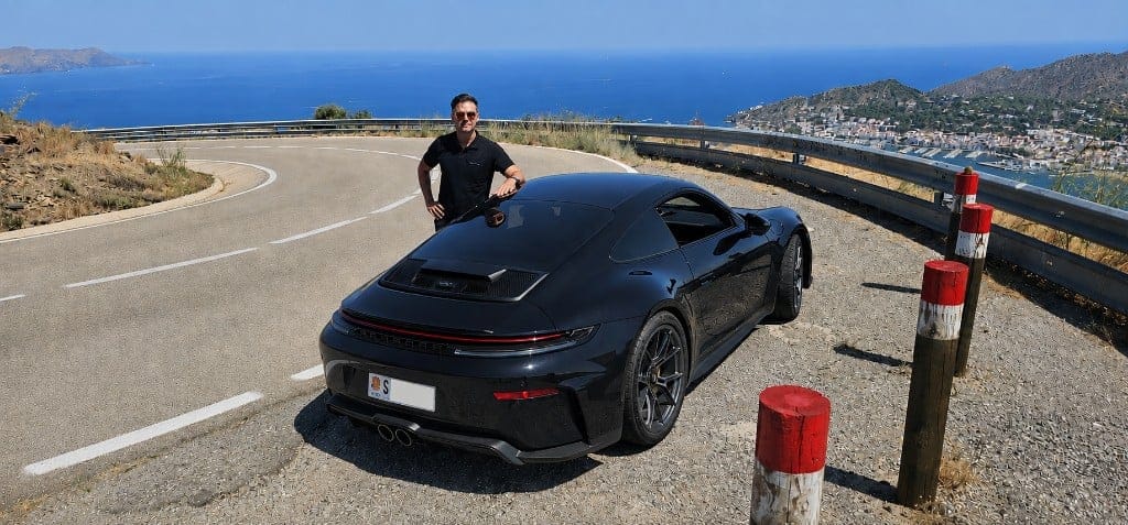 Ignacio Milán with a black Porsche on a coastal mountain road