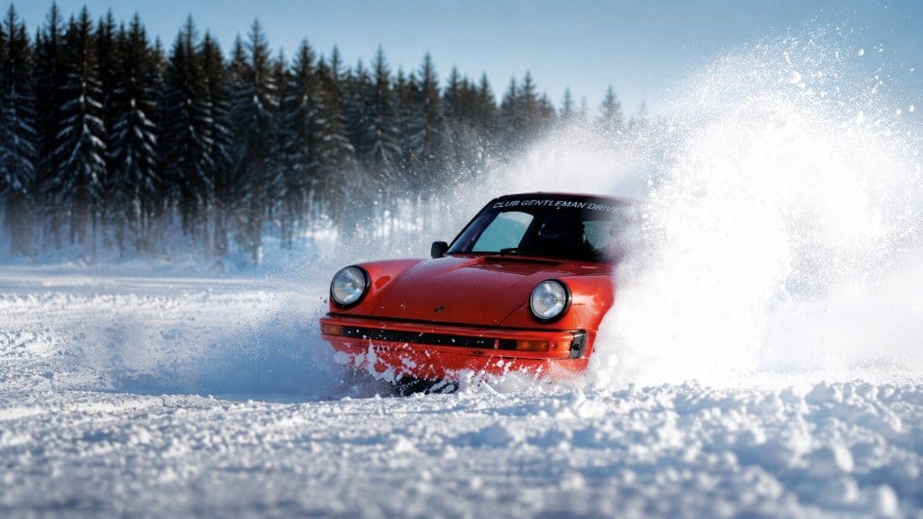 Orange classic Porsche kicking up snow at GTlife Winter Stage