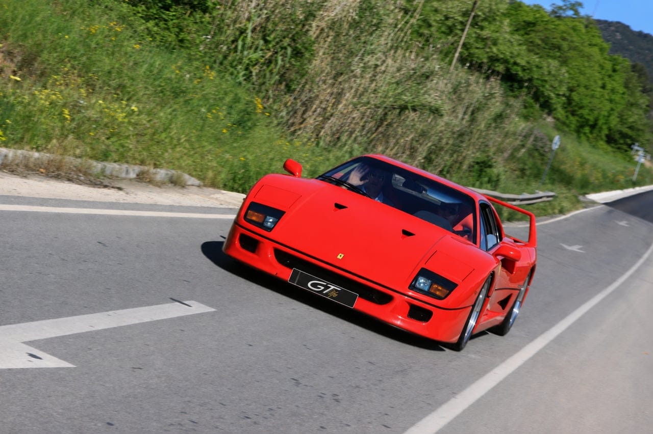 Red GTlife Ferrari F40 on the road, with the driver waving