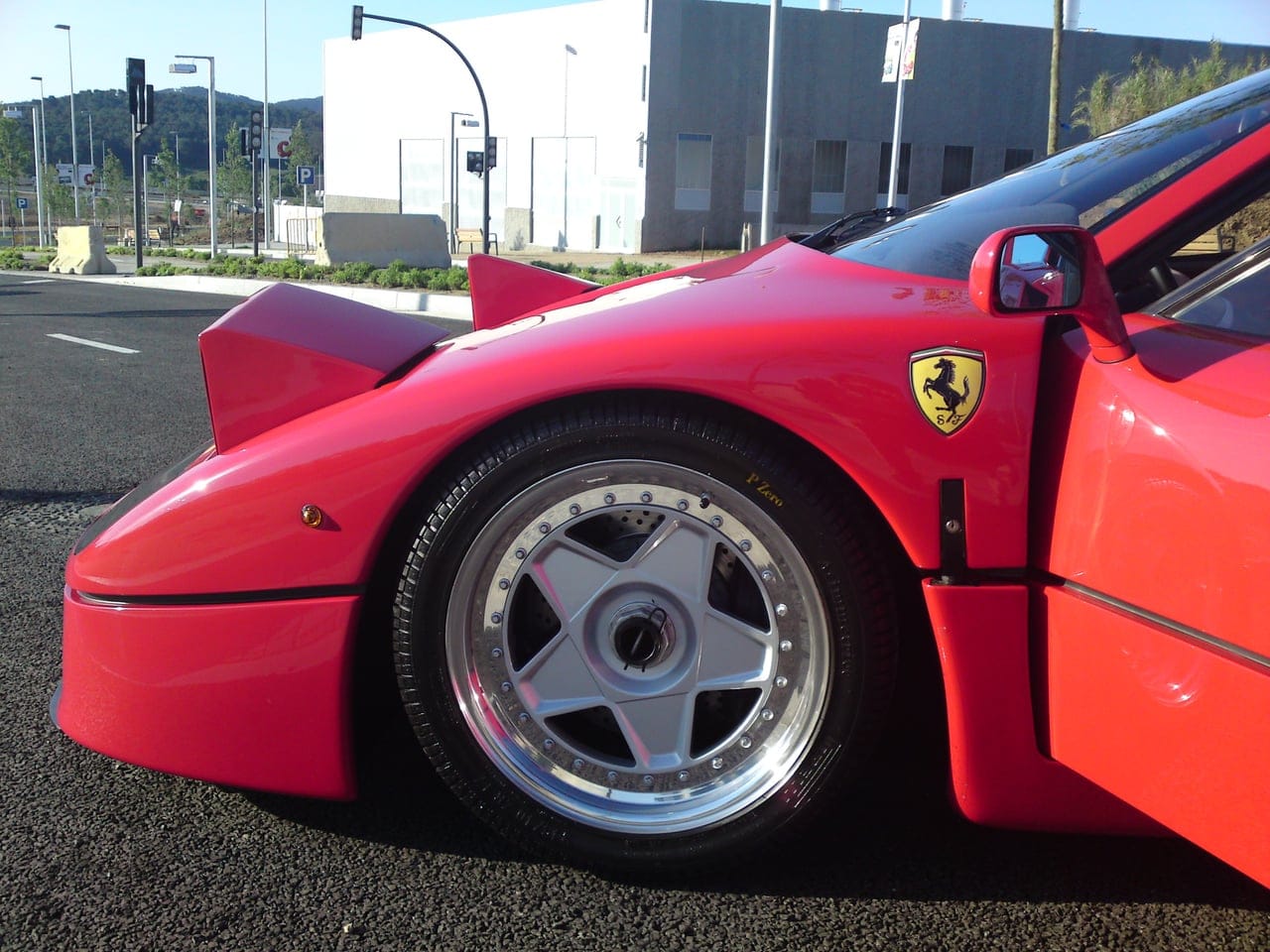 Red Ferrari F40 in profile with pop-up headlights raised